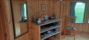 A wooden interior with a mirror, a table with kitchen items, a chair, and a window with a view of greenery. - Unique Retreat Sleeps 2 with Hot Tub & Pets Ok (Bantry)