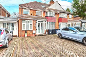 A residential area with houses, a paved driveway, and parked cars. - House Sleeps 11 with Free Parking & WiFi (Birmingham)