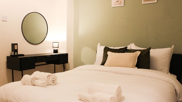 Una camera d'hotel con un letto, una scrivania, uno specchio e due quadri appesi al muro.