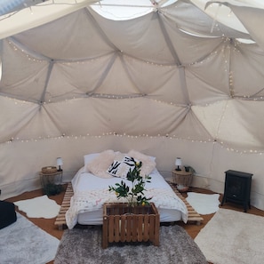 A cozy tented room with a bed, string lights, a small table, and a heater. - Charming Retreat in Pewsey Countryside (Pewsey)