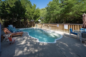 Ein Garten mit Swimmingpool, Liegestühlen und Holzzaun.