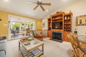 Ein Wohnzimmer mit Kamin, Fernseher und Essecke mit Stühlen und Tisch.