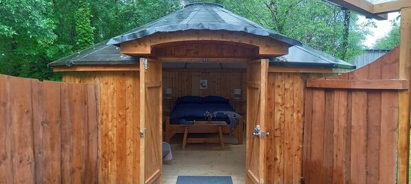 A wooden cabin with a bed, bedside tables, and a small window.
