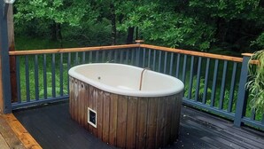 Un bain à remous sur une terrasse en bois, avec vue sur une forêt.