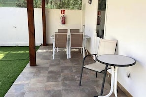 A covered patio area with a fire extinguisher mounted on the wall, a small round table, and two chairs. - Finca House by Fataga Maspalomas (San Bartolome de Tirajana)