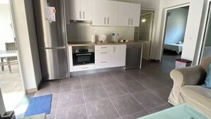 Een moderne keuken met roestvrijstalen apparatuur, witte keukenkastjes en een betegelde vloer.