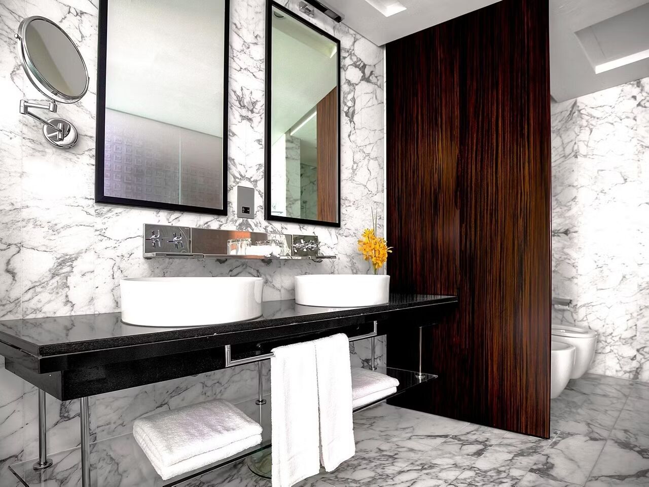 A bathroom with two sinks, a mirror, a towel rack, and a wooden door.