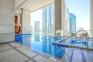 Une piscine à débordement située sur le toit, offrant une vue sur la ville, dotée d’une balustrade en verre et présentant un design architectural moderne.