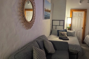 Une chambre avec un canapé, un lit avec des oreillers, un miroir et une porte.