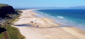 Une route côtière bordée d’une plage et de falaises.