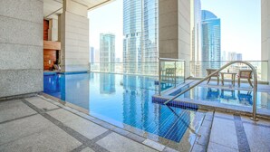 Ein Pool mit Wasserspiegel im Freien auf dem Dach, mit Blick auf die Stadt, einer Glasuhr und einem modernen architektonischen Design.