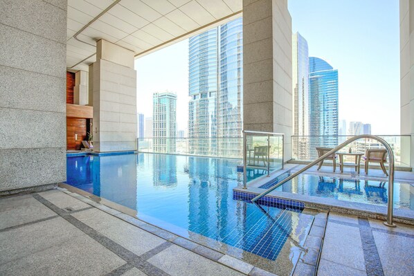Ein Pool mit Wasserspiegel im Freien auf dem Dach, mit Blick auf die Stadt, einer Glasuhr und einem modernen architektonischen Design.