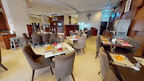 A hotel dining area with multiple tables and chairs, a reception desk, and a modern interior design. - Sig Al Barsha | Superior Room | Sheikh Zayed Rd, Gym + Salon, Nightclubs (Dubai)