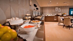 A buffet with various desserts and a seating area with chairs.