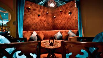 Un coin salon accueillant avec une table ronde, des sièges confortables et une lanterne décorative.