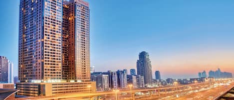 A high-rise building with the name 'Mercure' on its facade, surrounded by other tall buildings and a busy highway with overpasses.