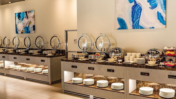 Ein reichhaltiges Buffet mit mehreren Servierstationen, jeweils mit einem Glaskonthaus und einem Metalldeckel, sowie einer digitalen Uhr, die die Uhrzeit anzeigt.