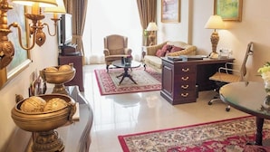Ein Hotelzimmer mit Sofa, Sessel, Schreibtisch, Lampe und Dekoration.