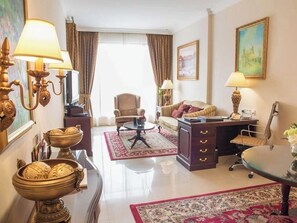 A hotel room with a sofa, armchair, desk, lamp, and decorative items. - 1BR City | Mercure BH | Metro Facing, Pool, Squash Pool, Kids Club (Dubai)