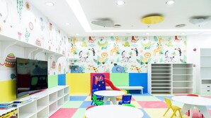 Un'area giochi per bambini con pareti colorate, una televisione, un'area dedicata al gioco e posti a sedere.