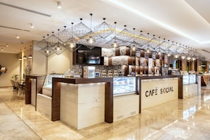 A modern café with a marble countertop, geometric pendant lighting, and a TV screen. - 1BR City | Mercure BH | Metro Facing, Pool + Gym | 2 Units (Dubai)