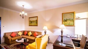 Ein Wohnzimmer mit einer Couch, Sesseln, einem Couchtisch, einer Chandelier und zwei Lampen.