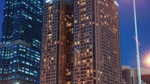 A high-rise building with illuminated signage, a modern architectural design, and a view of the surrounding urban landscape. - Mercure BH | 1BR Sky Apt | Spacious Living on Sheikh Zayed Rd | 2 Units (Dubai)