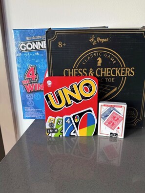 A UNO game box, a 4 of hearts playing card, and a chess & checkers game box. - 2-bedroom apartment in tranquil Birmingham with AC for relaxing stays (Birmingham)