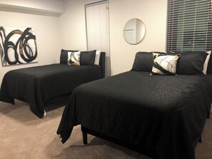 A room with two beds, a large abstract painting, a round mirror, and a window with blinds. - 2-bedroom apartment in tranquil Birmingham with AC for relaxing stays (Birmingham)
