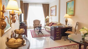 Een comfortabel ingerichte woonkamer met een bank, fauteuil, bureau en decoratieve objecten.