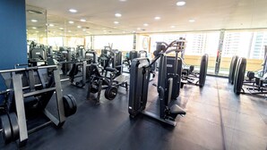 Een sportschool met diverse fitnessapparaten, een spiegelwand en grote ramen.