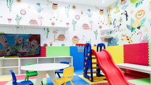 Een kinderspeelruimte met kleurrijke muren, een speelgedeelte en een televisie.