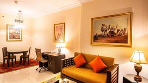 A hotel room with a dining area, a sofa, a desk, and two lamps.