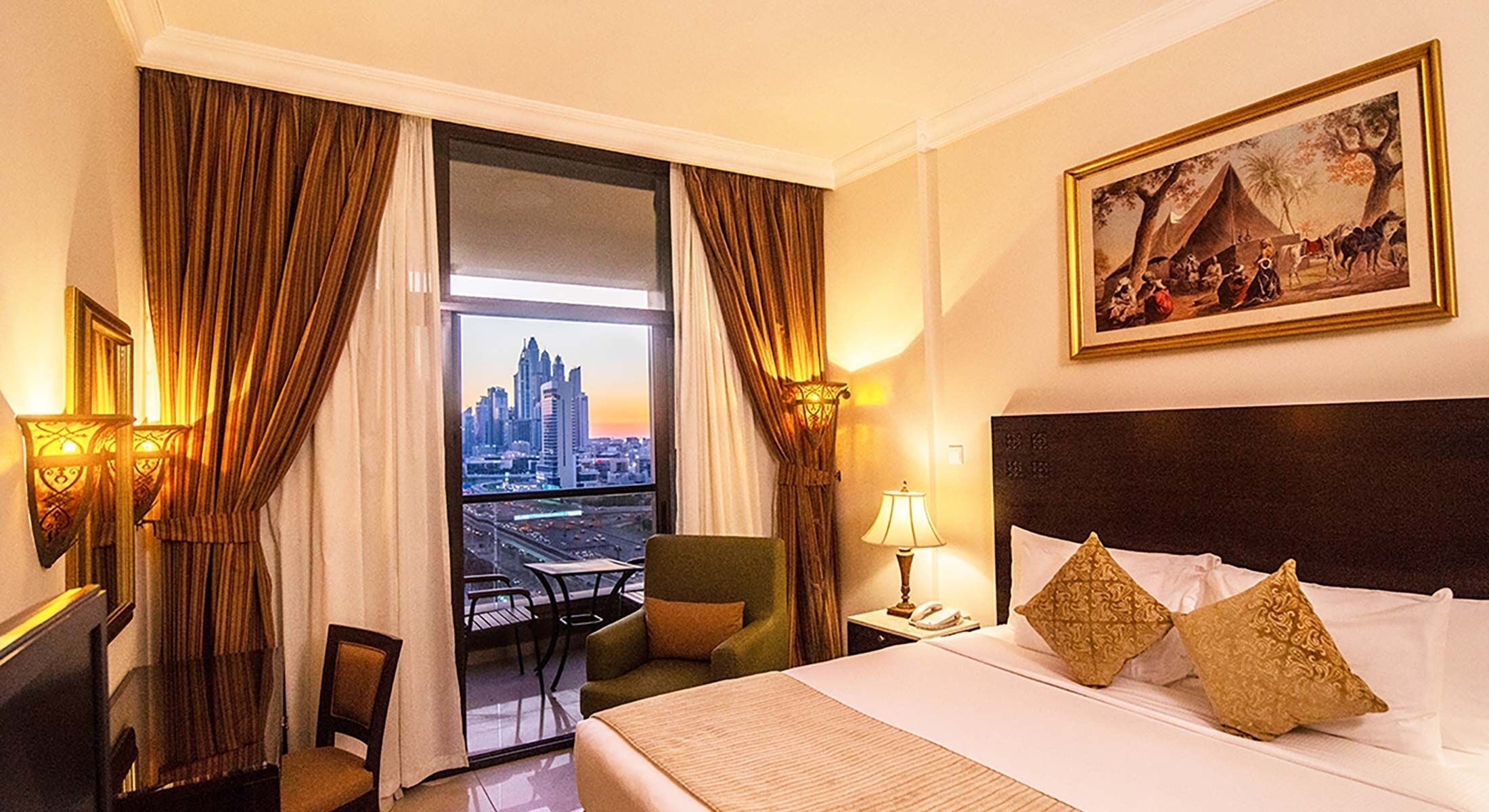 A hotel room with a bed, a chair, a desk, a lamp, and a painting.