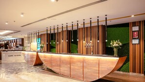 A reception desk with a curved design, a 'CAFE SOCIAL' sign, and a green wall with vertical wooden slats.