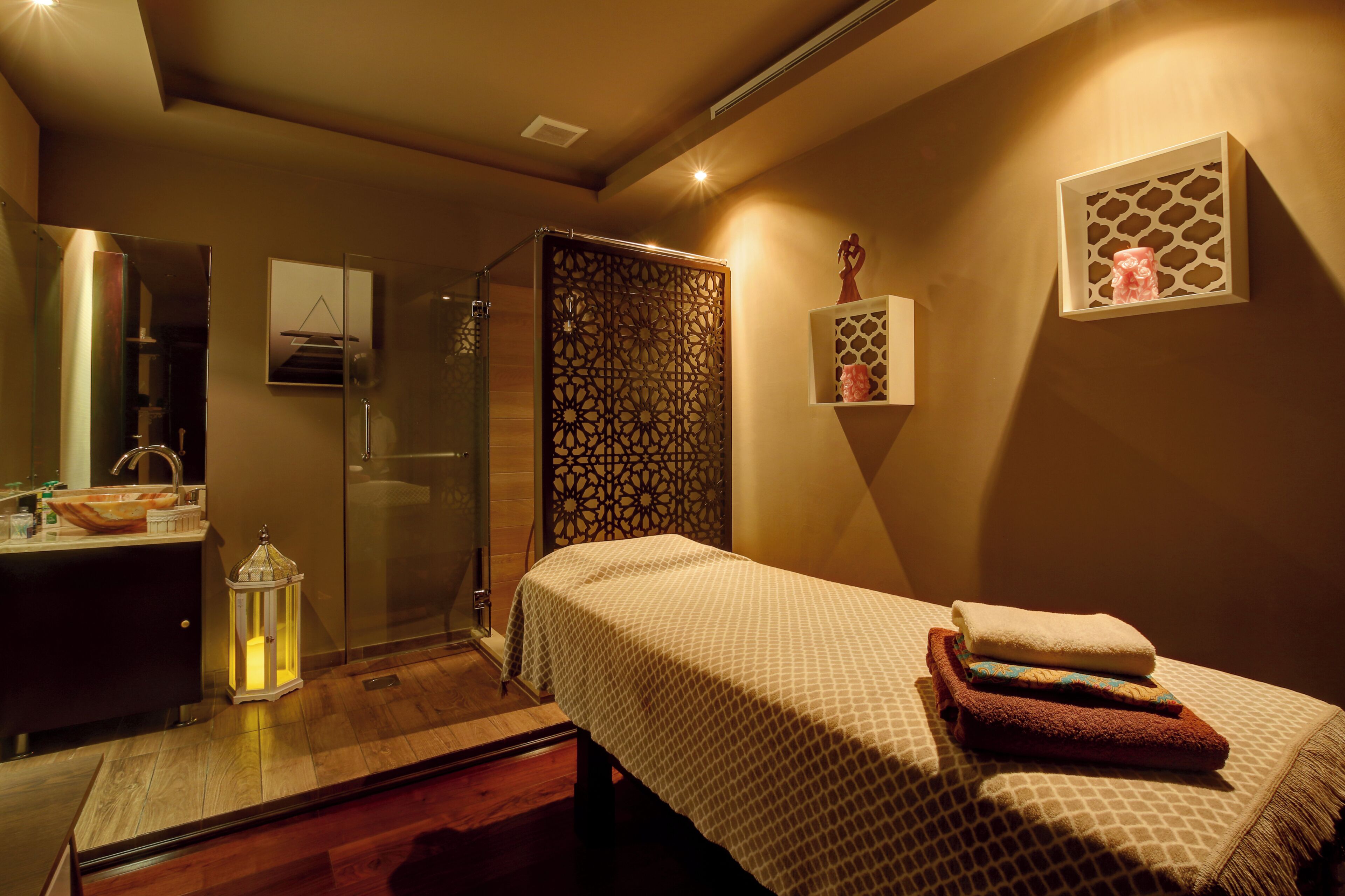 Een hotelkamer met een bed, nachtkastje, spiegel en douche.