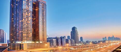 A high-rise building with the name 'Mercure' on its facade, surrounded by other tall buildings and a busy highway with overpasses.