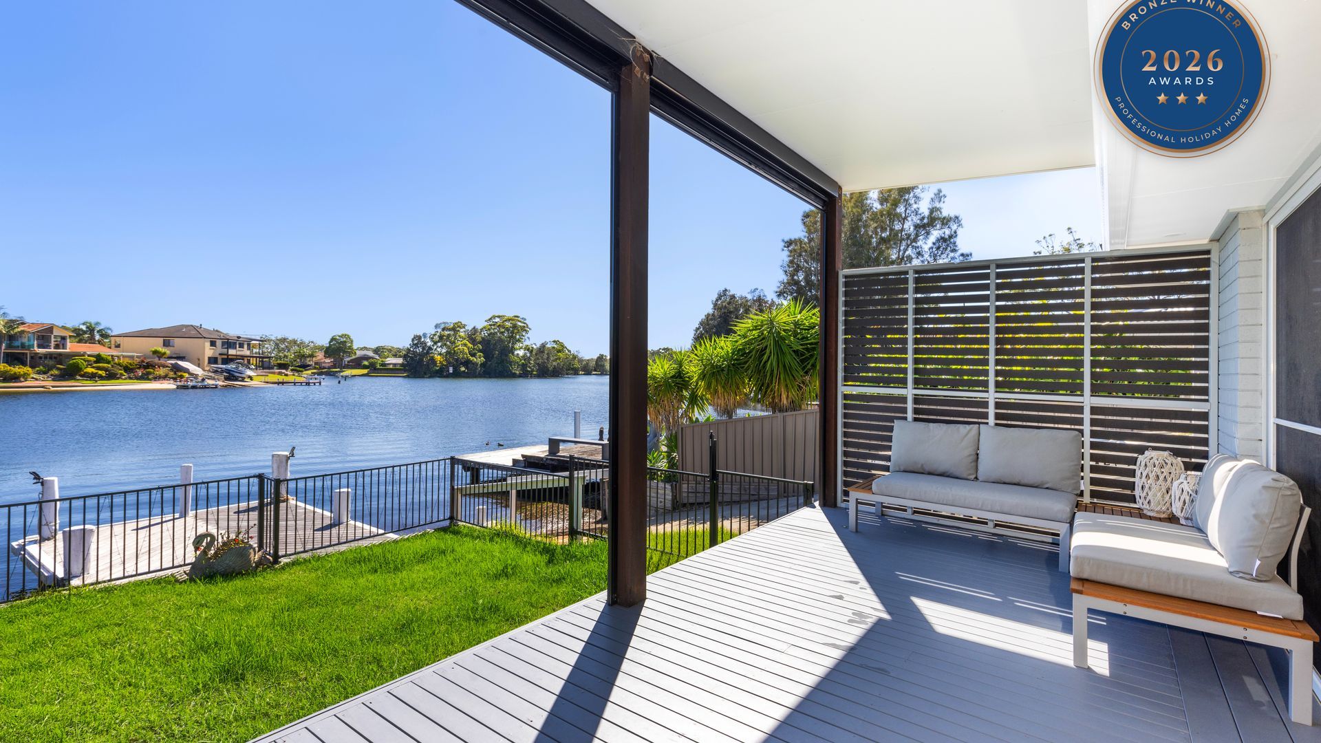 A balcony with a view of a lake, a seating area with cushions, and a plaque indicating a 2026 award.