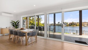 A spacious room with a large sliding glass door leading to a deck overlooking a body of water.