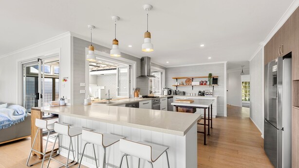A modern kitchen with a central island, bar stools, and pendant lighting.