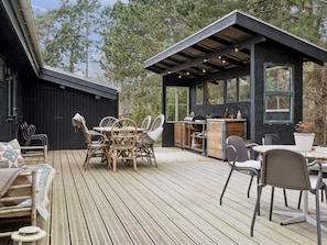 A wooden deck with outdoor furniture, a barbecue area, and a small building with windows. - 4 Star Holiday Home in Hojby (Hojby)