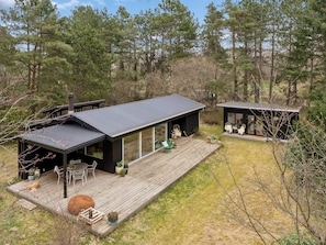 A modern cabin with a large deck, outdoor seating, and a glass-enclosed porch. - 4 Star Holiday Home in Hojby (Hojby)
