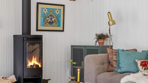 Ein gemütliches Wohnzimmer mit Kamin, Sofa, Lampe und einem gerahmten Bild an der Wand.