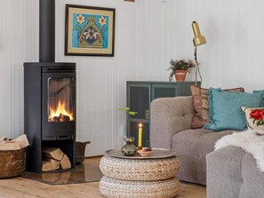 Ein gemütliches Wohnzimmer mit Kamin, Sofa, Lampe und einem gerahmten Bild an der Wand.