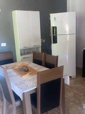 A dining area with a table, chairs, a cabinet, and a refrigerator.