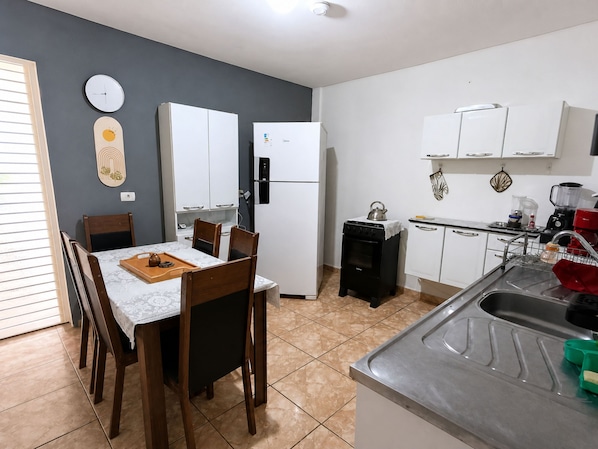 A kitchen with a dining table, chairs, a stove, a refrigerator, and a sink.