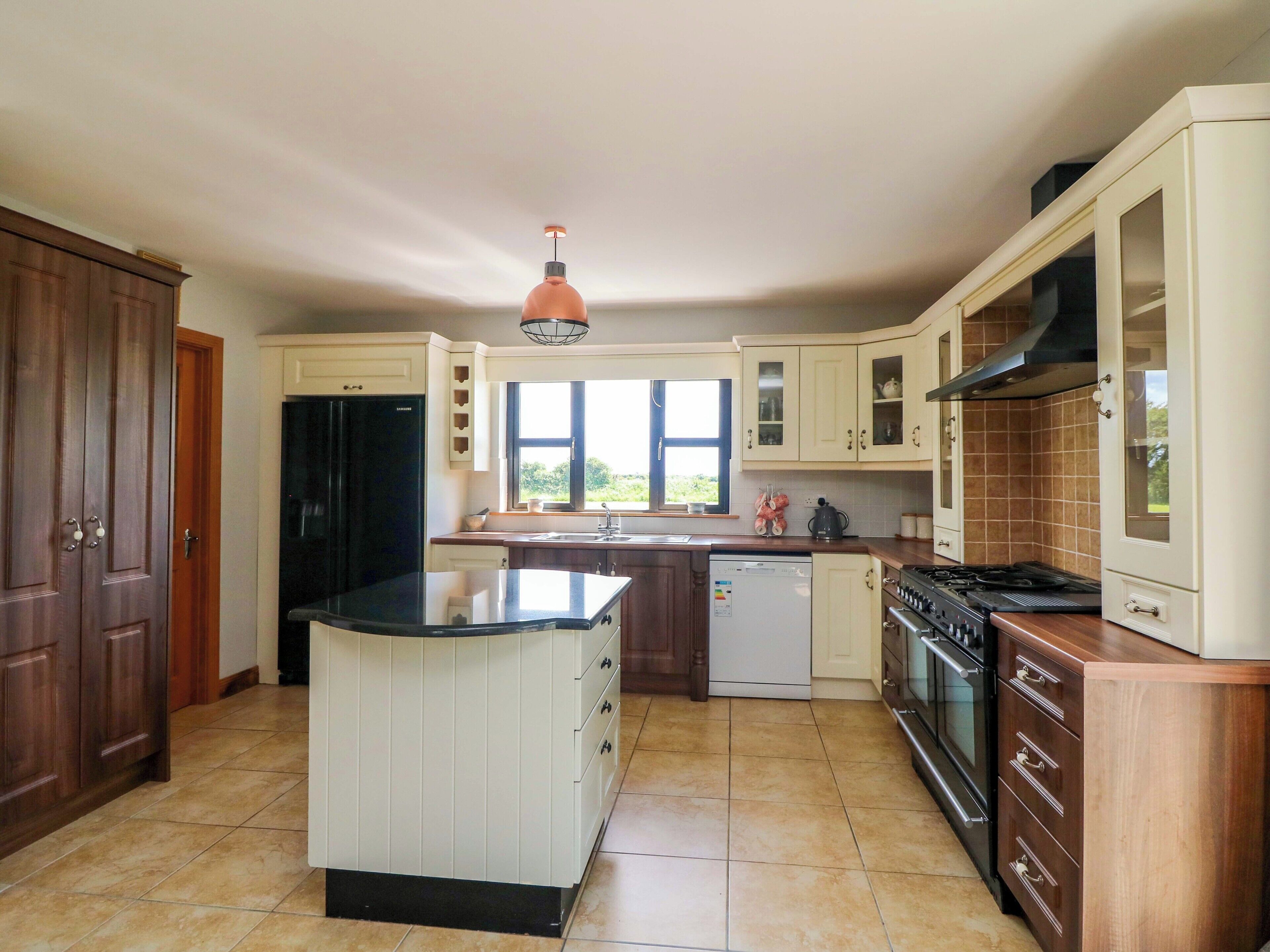 A kitchen with a central island, a stove, a dishwasher, and wooden cabinets.