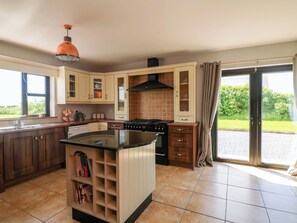 Une cuisine moderne dotée d’un îlot central, de meubles de rangement intégrés, d’une cuisinière et d’une grande fenêtre.