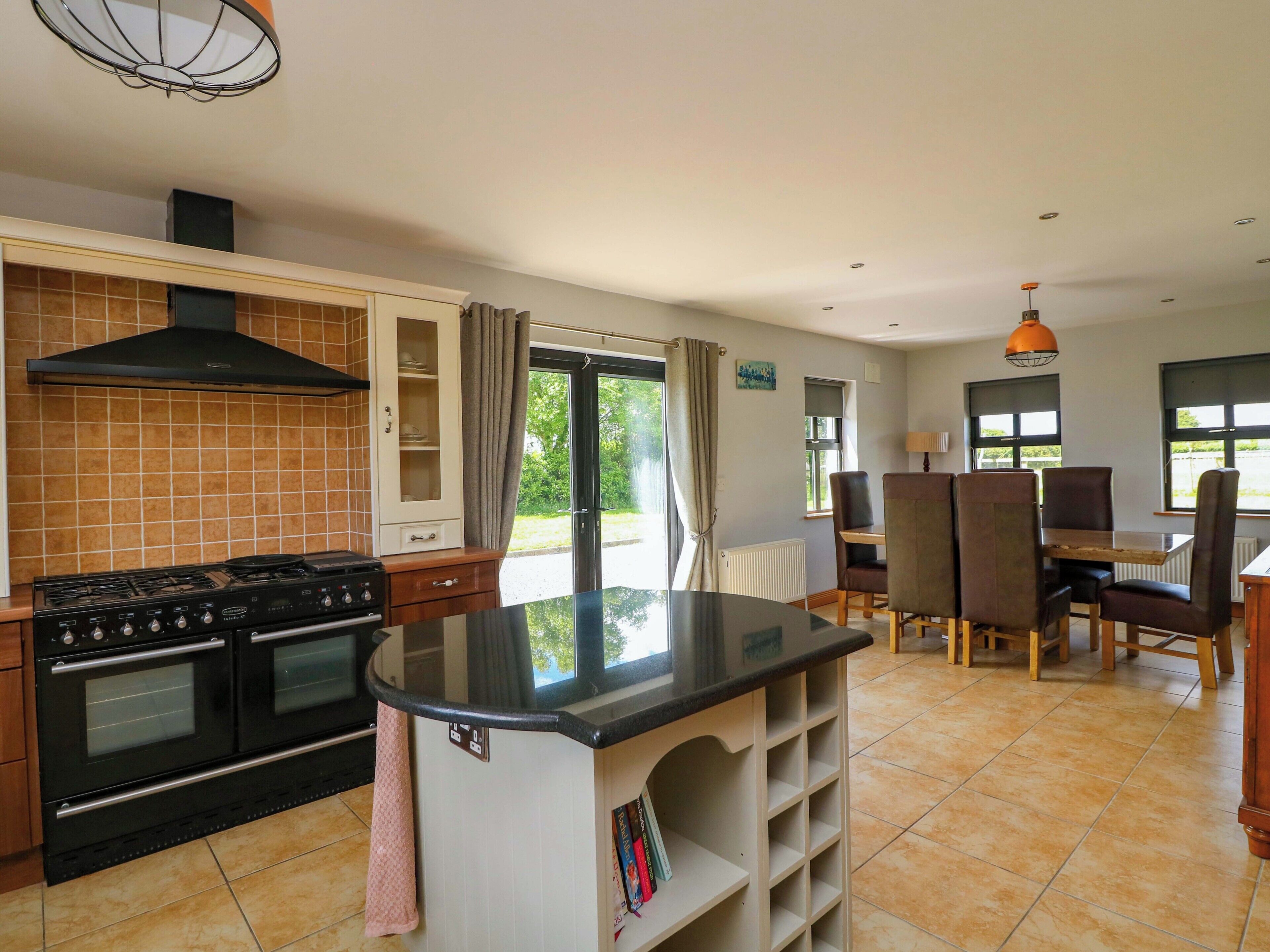 A kitchen with a stove, oven, and a dining area with chairs and a table.