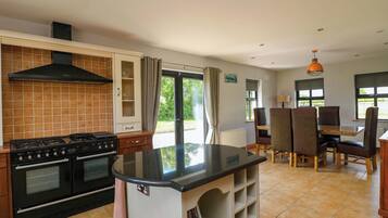 A kitchen with a stove, oven, and a dining area with chairs and a table.